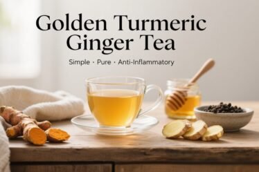 Clear glass mug of turmeric ginger golden tea on a rustic wooden countertop with fresh turmeric, ginger, and honey — anti-inflammatory wellness drink.